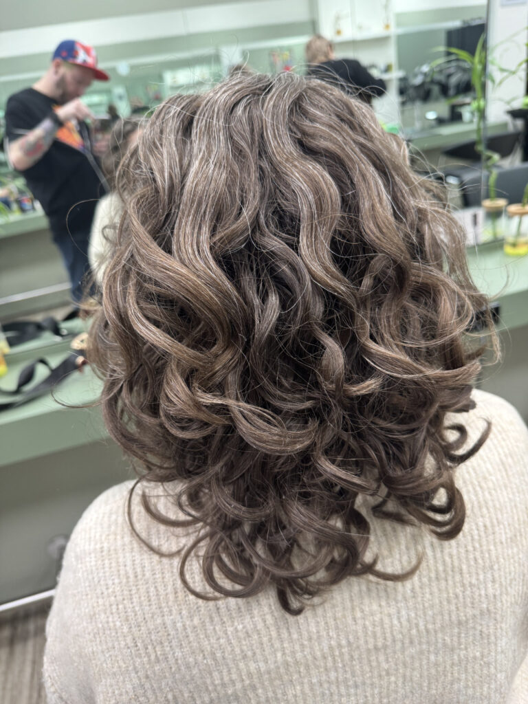 Sascha Mylenbusch - Dauerwelle in Düsseldorf, Benrath - Rückseite einer brünetten Frau mit einem stylischen Lockenschnitt im Salon in Düsseldorf